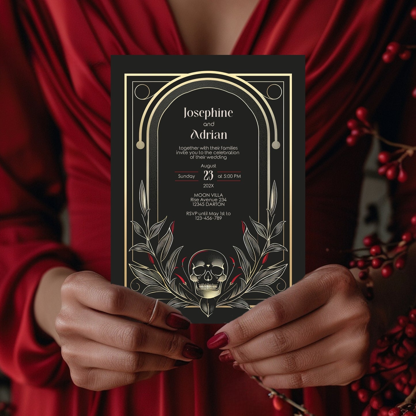 Person holding a black wedding invitation with gold details and a skull design.