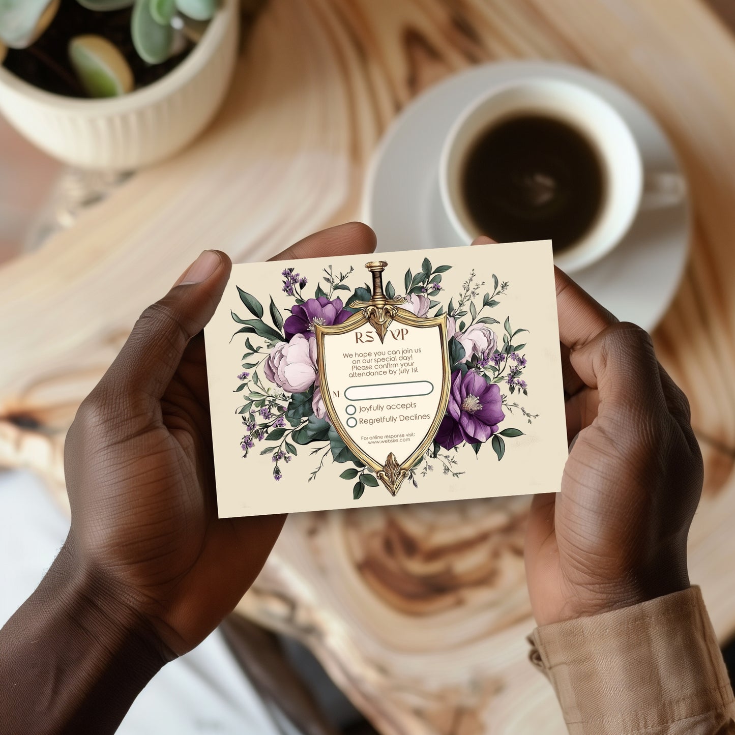 Person holding a floral RSVP card with a cup of coffee and plant in the background