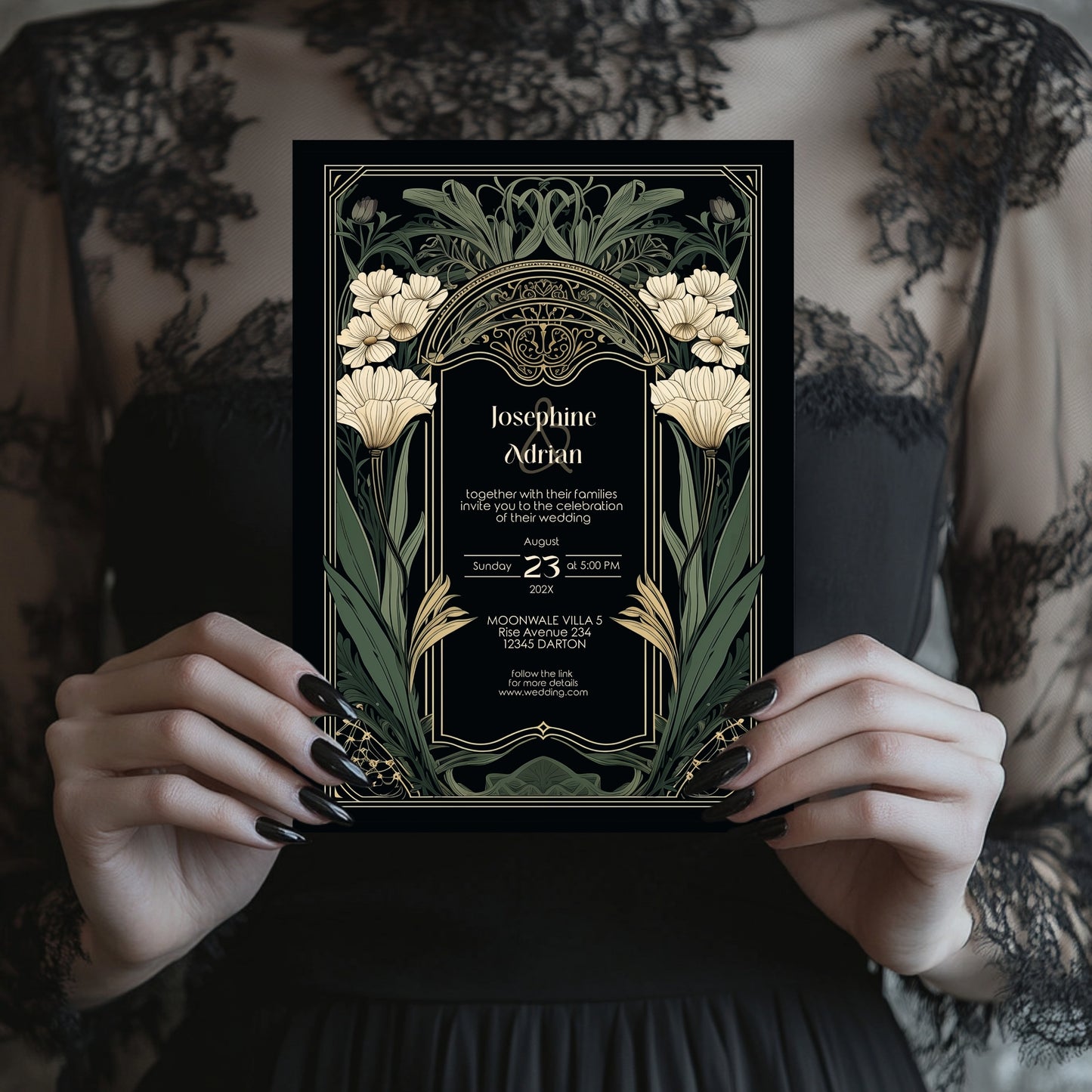 Art Nouveau-style wedding invitation held by hands with black nail polish against a patterned background.