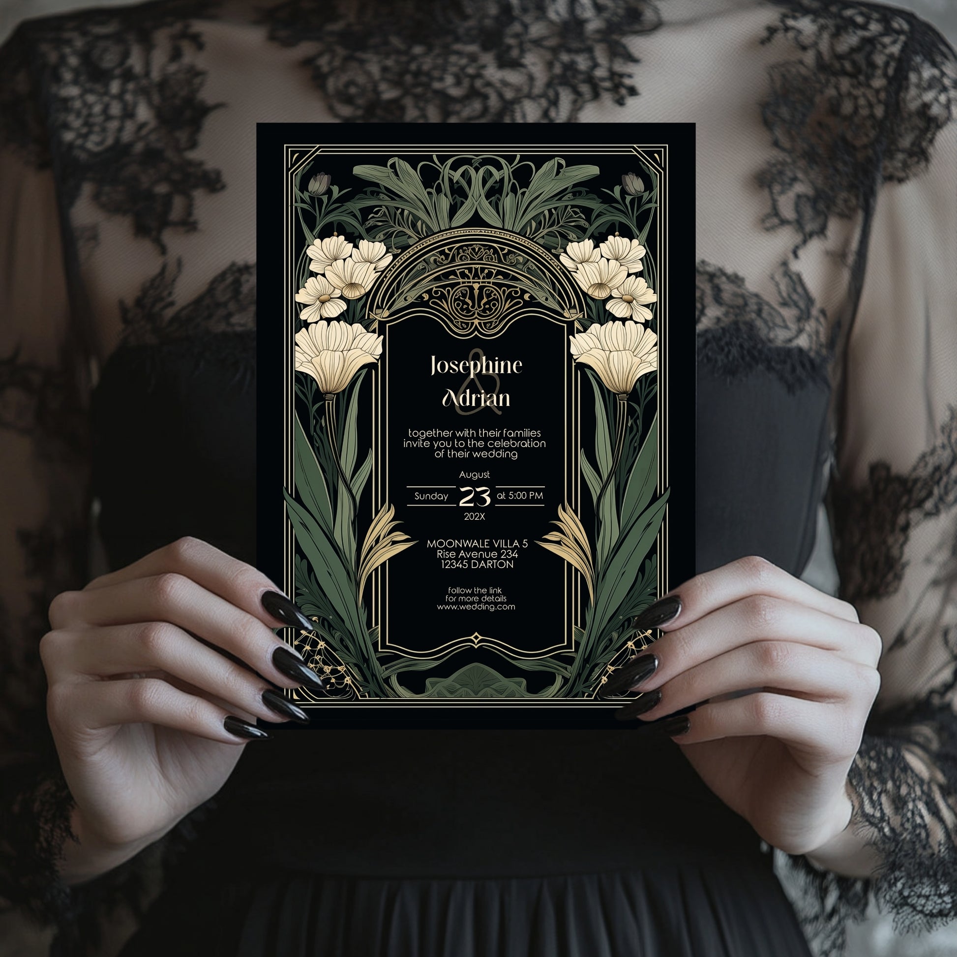 Art Nouveau-style wedding invitation held by hands with black nail polish against a patterned background.